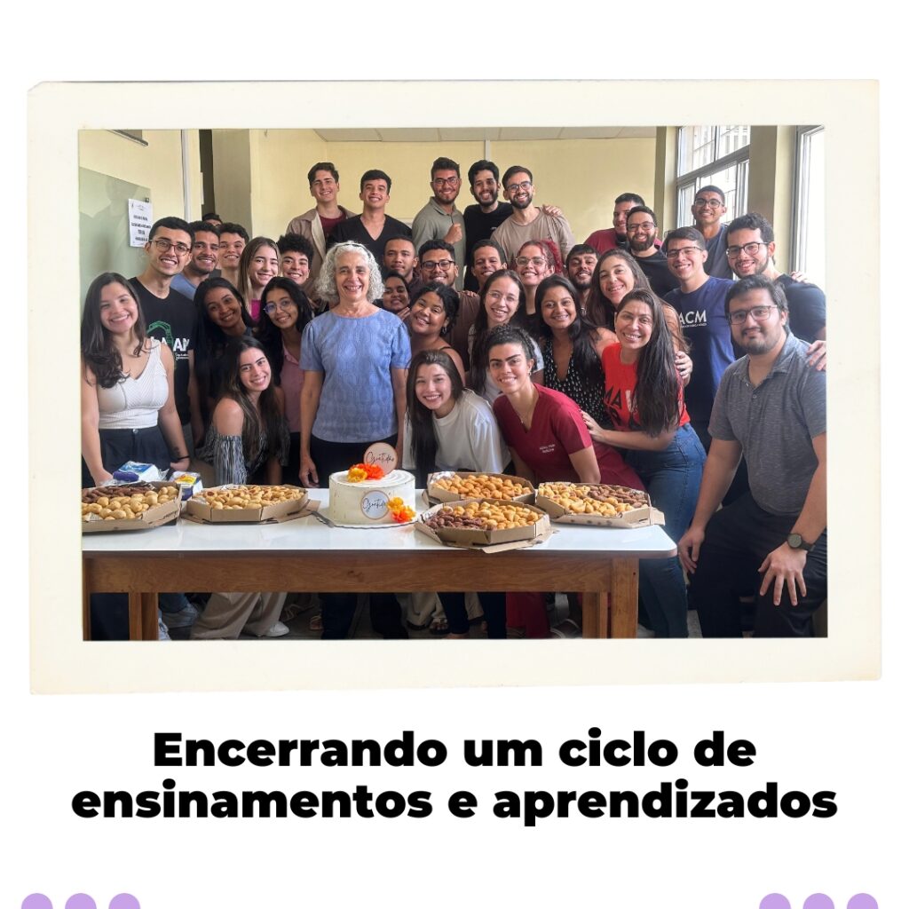 Dra. Maria dos Remédios Branco, cercada por um grupo de estudantes de medicina sorridentes, em uma sala de aula, celebrando sua aposentadoria da UFMA. Há uma mesa na frente com bolos e salgados, simbolizando a comemoração.