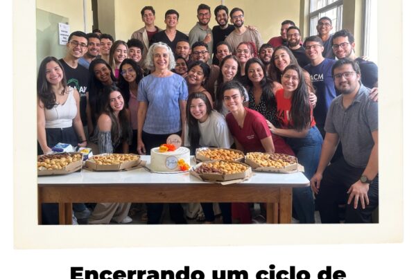 Dra. Maria dos Remédios Branco, cercada por um grupo de estudantes de medicina sorridentes, em uma sala de aula, celebrando sua aposentadoria da UFMA. Há uma mesa na frente com bolos e salgados, simbolizando a comemoração.