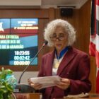 Dra. Maria dos Remédios Branco discursa na tribuna da Assembleia Legislativa do Maranhão durante a cerimônia de entrega da Medalha de Mérito Legislativo Jackson Lago, usando a medalha no peito e segurando o discurso impresso.