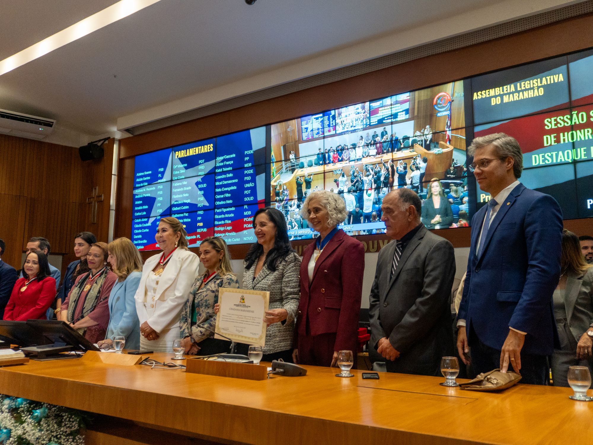 Autoridades e mulheres homenageadas, entre elas Maria dos Remédios Branco, posam para foto oficial com medalhas e certificados durante sessão solene da Assembleia Legislativa do Maranhão.