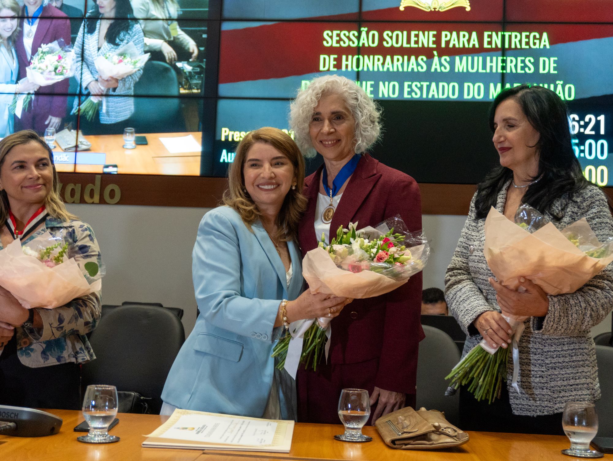 A deputada Iracema Vale entrega flores à Dra. Maria dos Remédios durante a cerimônia de entrega da Medalha do Mérito Legislativo Jackson Lago, na Assembleia Legislativa do Maranhão.